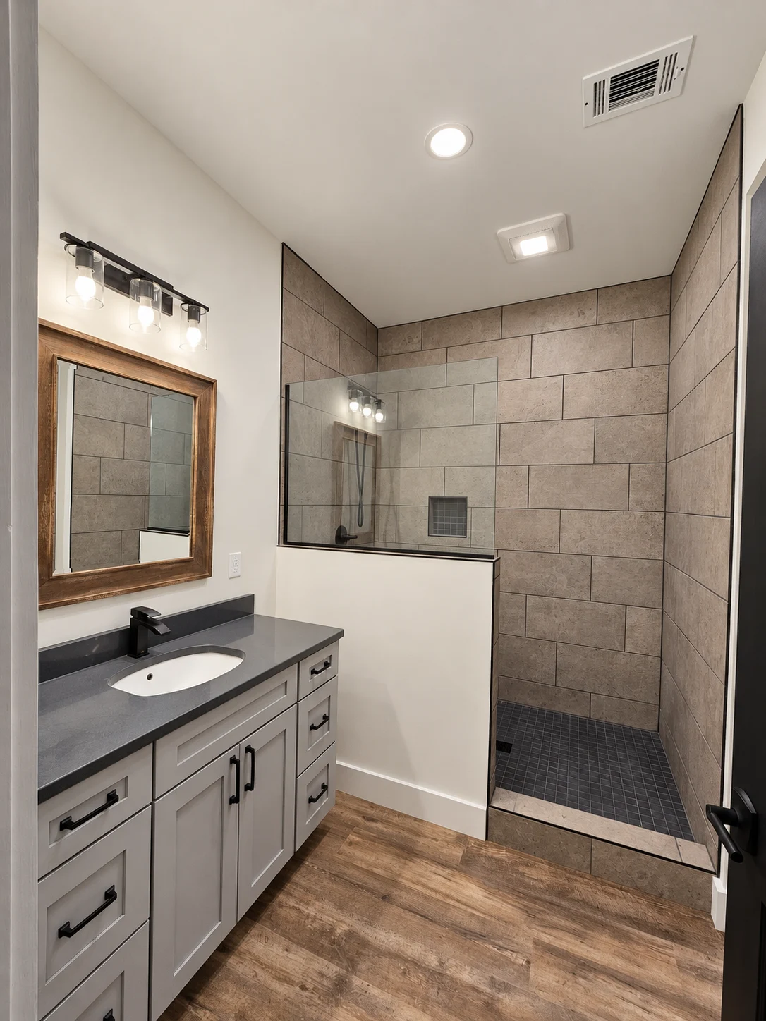 Finished bathroom with gray vanity and tiled walk-in shower