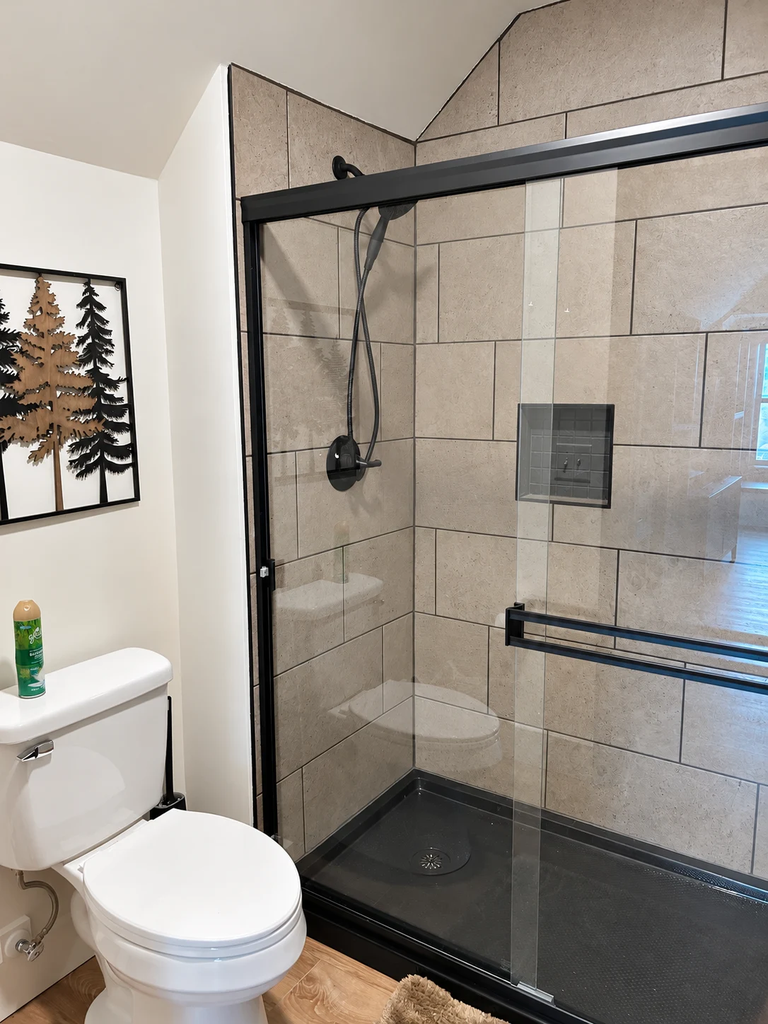 Taupe tiled shower with black glass frame and fixtures